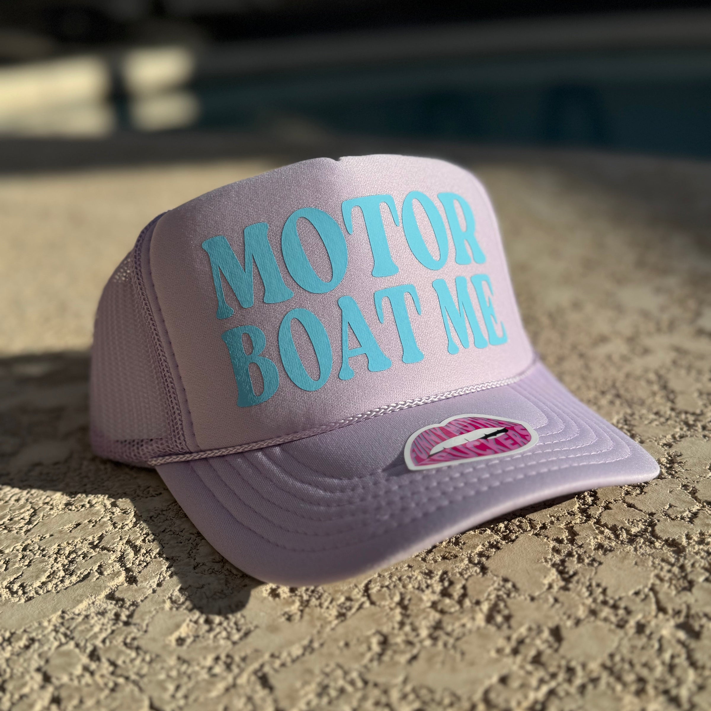 Purple cap with 'Motor Boat Me' text on a textured surface