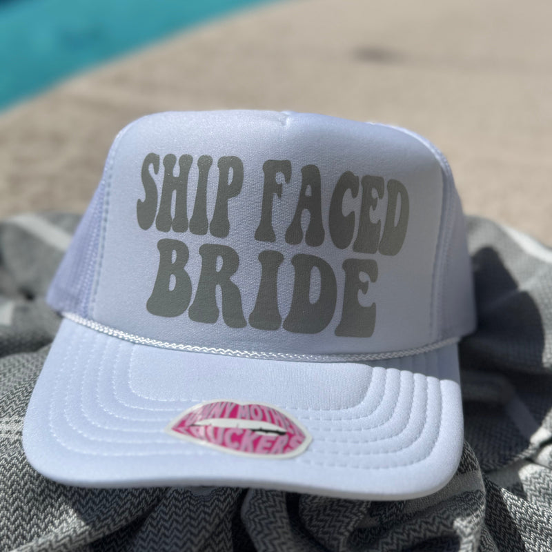 Gray cap with 'SHIP FACED BRIDE' text on a towel by a pool